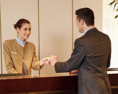 Hotel front desk clerk handing key card to customer